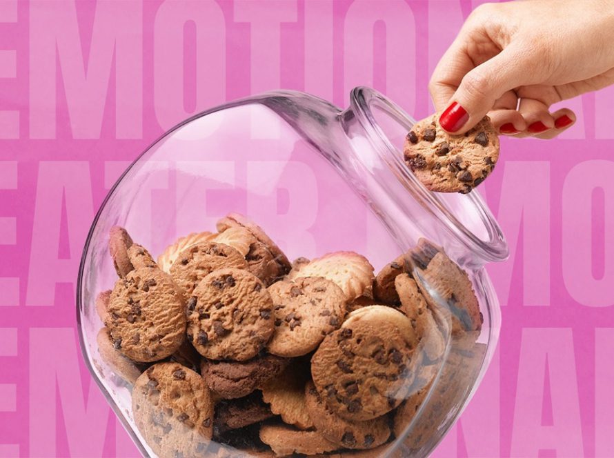 Womens hand reaching for a jar of biscuits and taking one out with words emotional eater on a pink background