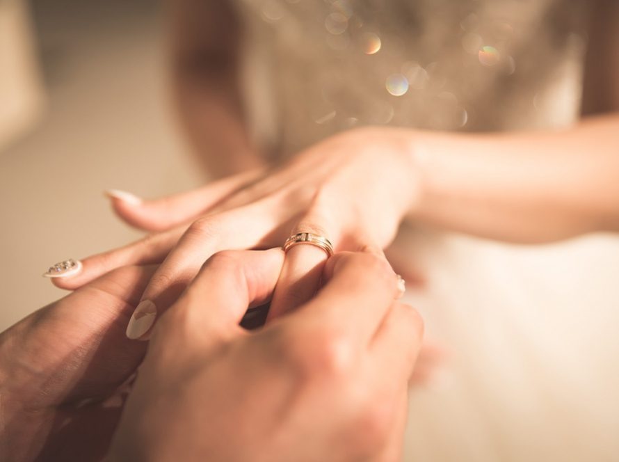 Female holding out her hand whilst wedding ring is placed on her finger