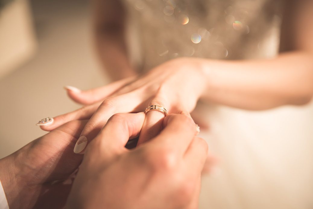 Female holding out her hand whilst wedding ring is placed on her finger