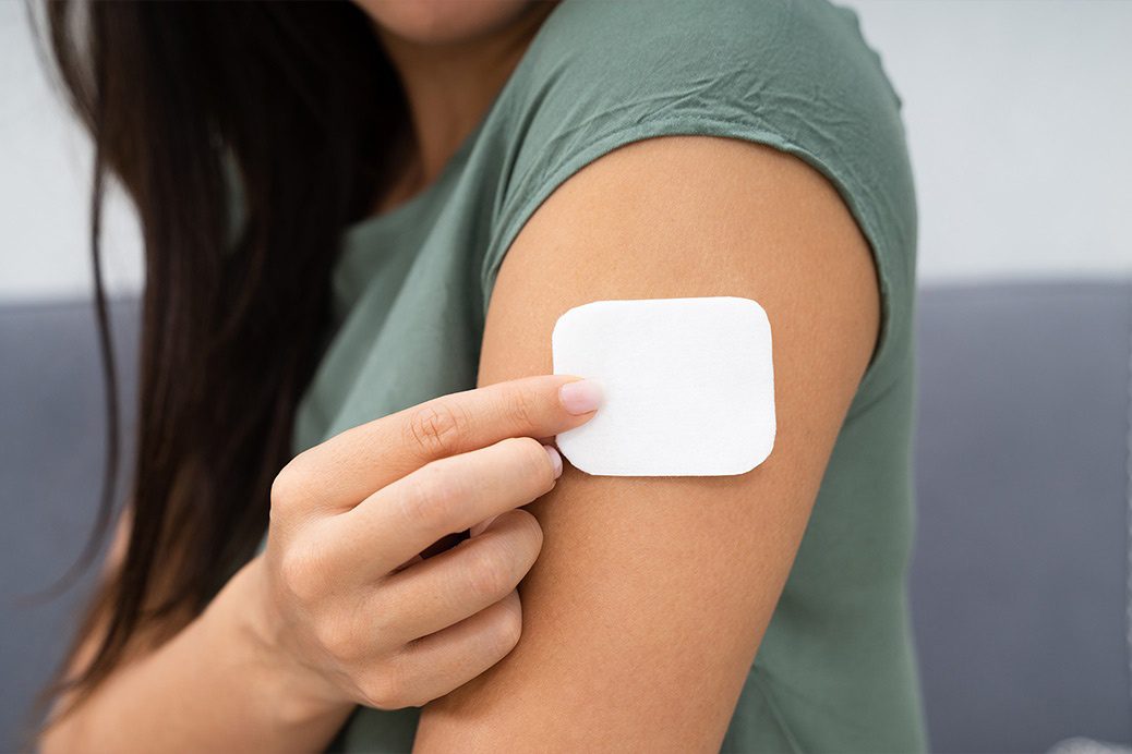 A female placing an HRT patch on her arm