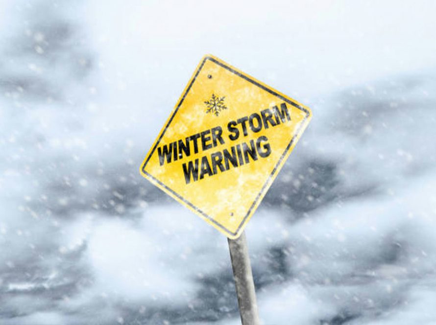A yellow sign that reads "Winter Storm Warning" and the background is snow